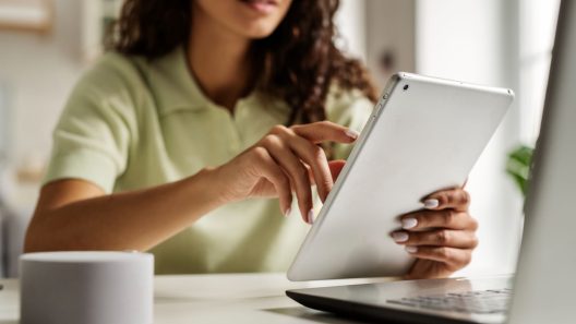 A woman reading iPad and sit near laptop