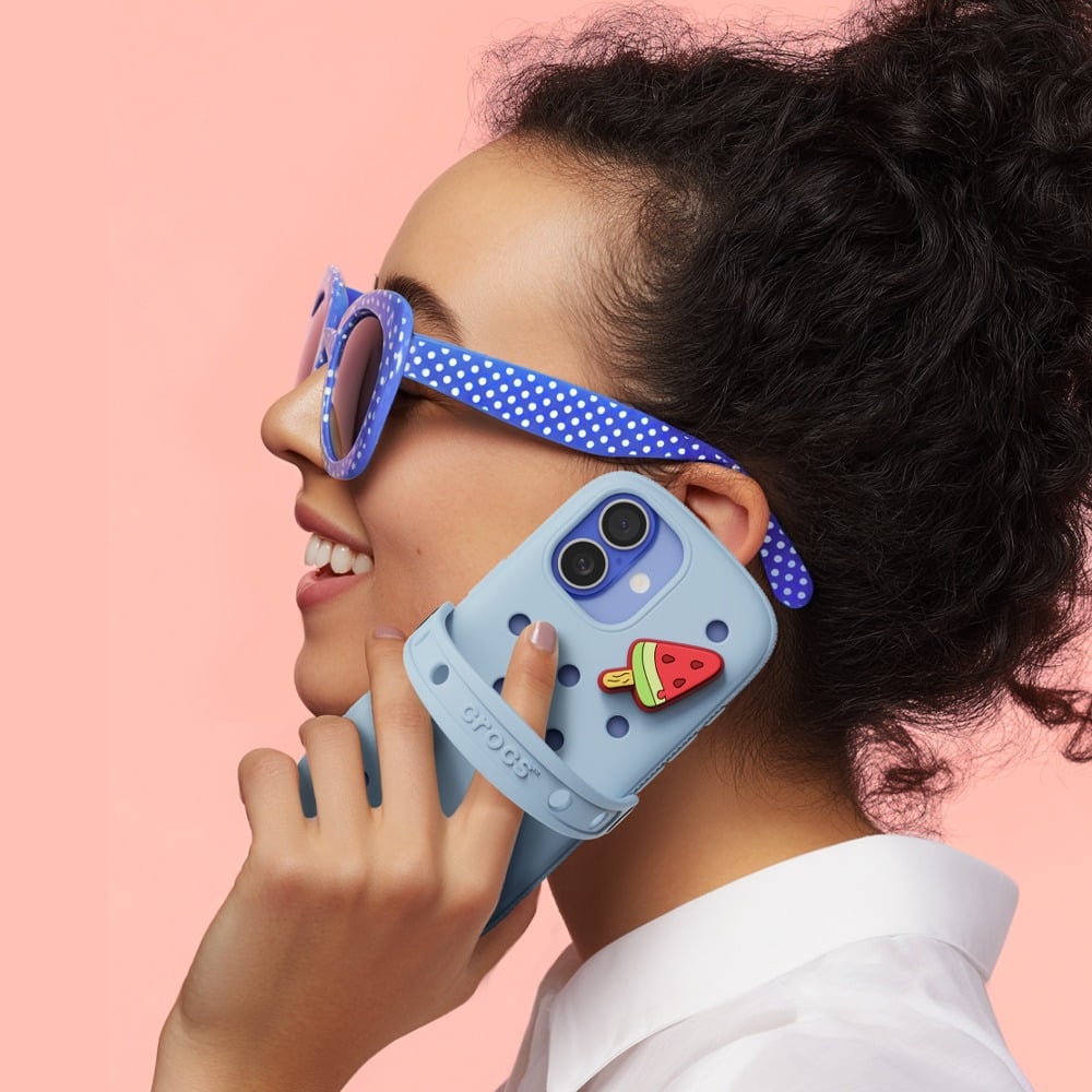 A girl holding Crocs smartphone case by the ear