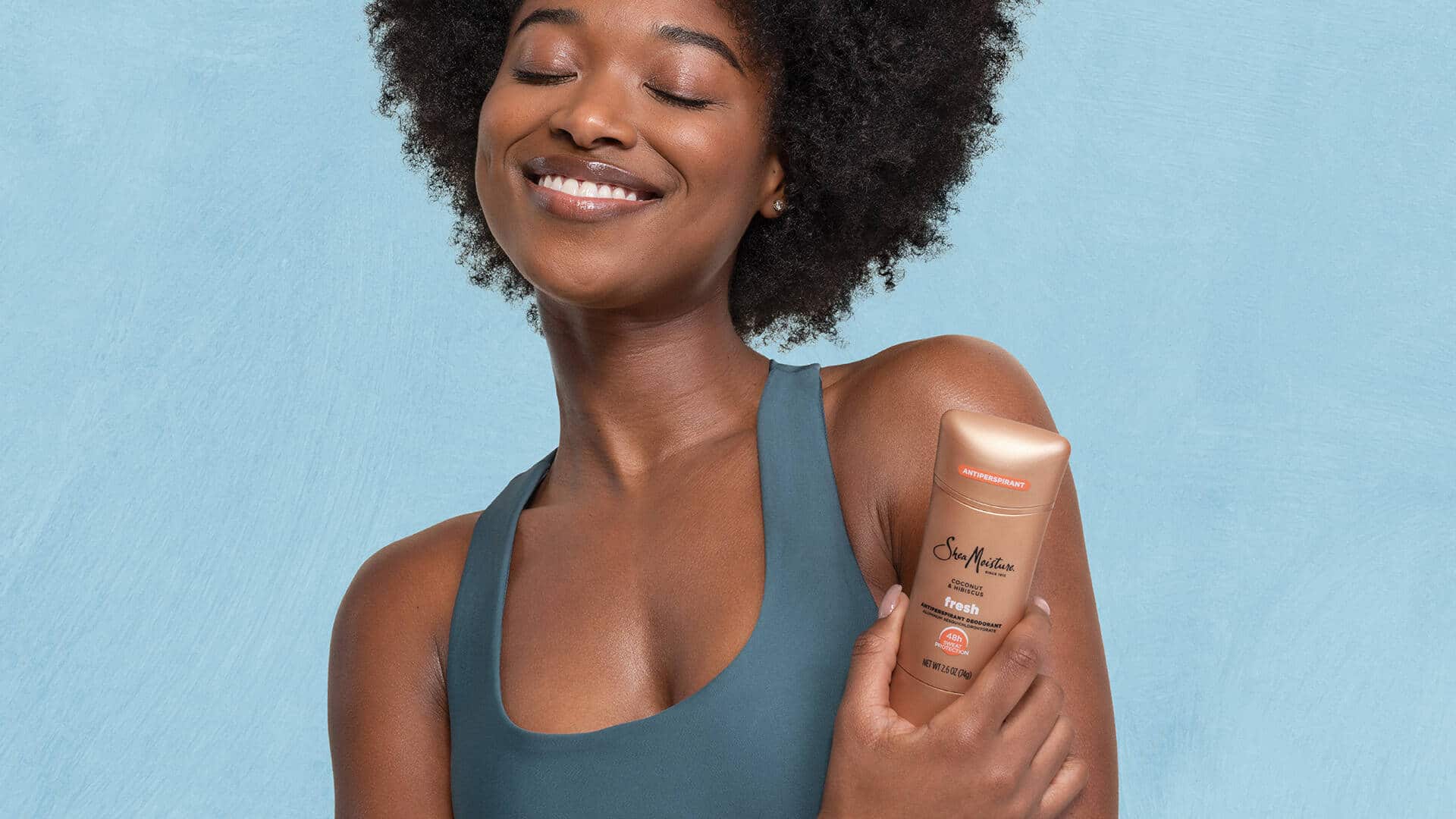 A smiling women with SheaMoisture deodorant in hand
